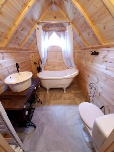 ein Badezimmer mit einer Badewanne und einem Waschbecken in einem Baumhaus in der Unterkunft Le Kota Etable in La Chapelle