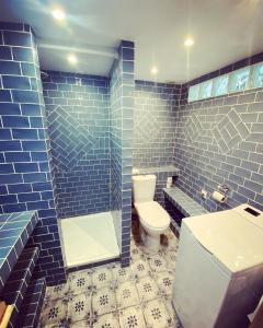 La salle de bains est pourvue de carrelage bleu, de toilettes et d'un lavabo. dans l'établissement Vaste loft plein de charme au cœur de Marseille, à Marseille