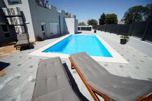 a swimming pool with two lounge chairs next to a building at Apartments Lulic in Zadar