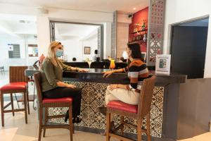 two women sitting at a bar wearing masks at Hotel María Jose in Mérida