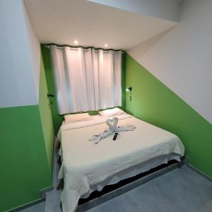 Maraca Hostel في ريو دي جانيرو: غرفة صغيرة خضراء مع سرير عليه فراشة