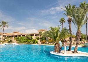 two people standing next to a swimming pool with palm trees at Camping Villasol in Benidorm