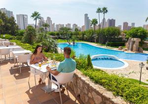 a man and woman sitting at a table next to a pool at Camping Villasol in Benidorm
