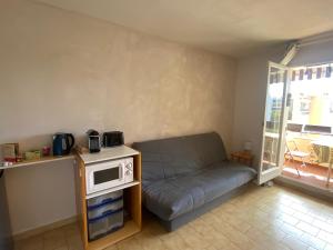 een woonkamer met een bank en een magnetron op een tafel bij Camargue Village Sun and Beach #1 5 Personnes in Le Grau-du-Roi