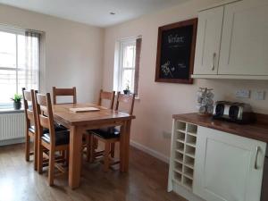a kitchen with a wooden table with chairs and a counter at Fir Tree Cottage in Blairgowrie