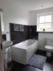 a bathroom with a tub and a sink and a toilet at Fir Tree Cottage in Blairgowrie