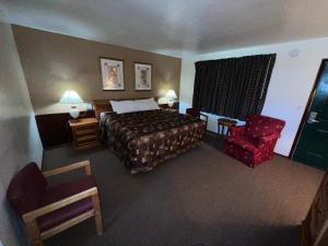 a bedroom with a bed, chair, desk and a lamp at Spinning Wheel Motel in Baraboo