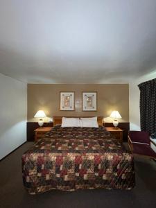 a hotel room with a large bed and two lamps at Spinning Wheel Motel in Baraboo