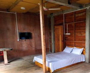 a bedroom with a bed and a tv on a wall at Jungle cottage in Sreemangal