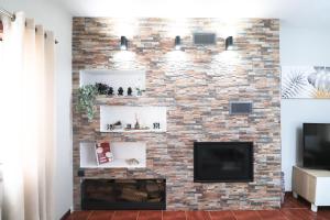 a living room with a brick fireplace and a tv at Casa da BellaVista in Ponte de Lima