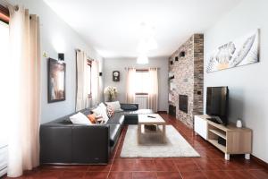 a living room with a black couch and a tv at Casa da BellaVista in Ponte de Lima