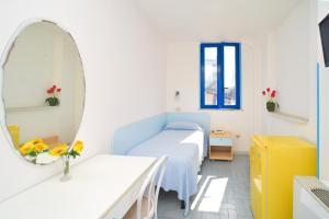 a white room with a bed and a mirror at Hotel Celeste in Procida
