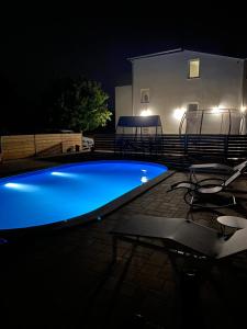 Holiday home “MARKO” with heated pool! في نين: مسبح في الليل مع كراسي ومنزل