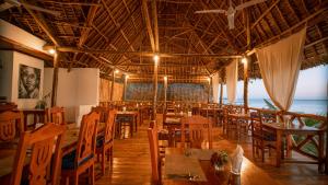 a restaurant with wooden tables and chairs and the ocean at Sansi Kendwa Beach Resort in Kendwa