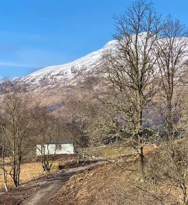 a snow covered mountain with a house on a dirt road at Sunset View Shepherds Hut in Dalmally