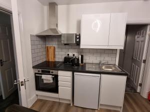 una piccola cucina con armadi bianchi e lavandino di Granada Apartments Derby Road a Blackpool