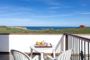 una mesa y sillas en un balcón con vistas al océano en Posada Punta Ballota, en Suances