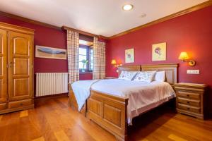 a bedroom with red walls and a bed with white sheets at Posada Punta Ballota in Suances