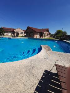 Cabañas de Ayui في كونكورديا: حمام سباحة ازرق كبير مع منزل في الخلفية