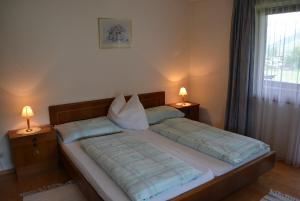 a bed in a bedroom with two lamps on tables at Pension Foidl in Waidring