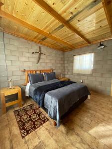 ein Schlafzimmer mit einem großen Bett und einer Holzdecke in der Unterkunft Cabaña San Tony in Valle de Guadalupe