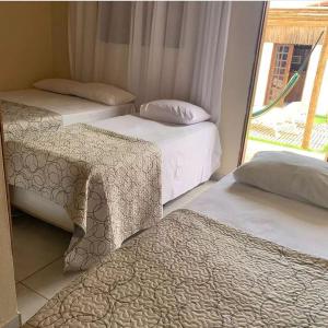 three beds in a room with a window at Pousada Flor De Jambú in São Miguel do Gostoso