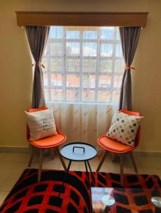 dwa krzesła i stół przed oknem w obiekcie Lovely apartment near town with WiFi and parking w mieście Meru
