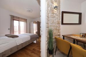 a bedroom with a bed and a table and a stone wall at Villa Dalmatino in Pakoštane