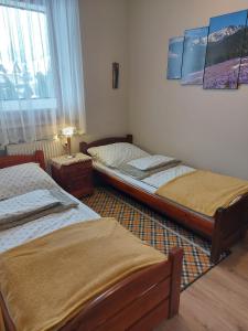 two twin beds in a room with a window at Apartament Zakopane Kamieniec 10i in Zakopane