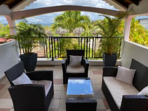 a balcony with chairs and a table and palm trees at Chez Soul~Etage entier avec vue sur mer in Sainte-Rose