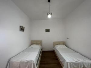 two beds in a room with white walls at Perdja Apartment II in Velipojë