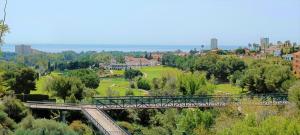 eine Brücke über einen Park mit Bäumen und einer Stadt in der Unterkunft Ample Luxury Apart Fancy Marbella Golf & Padel in Marbella