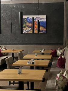 um restaurante com mesas de madeira e pinturas na parede em Jardis Boutique Hotel em Lana