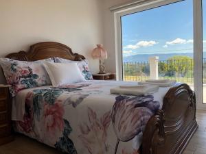 um quarto com uma cama com uma janela grande em SOLAR DA SERRA-GuestHouse em Mangualde