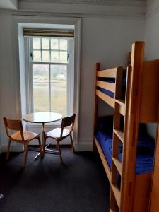 a room with a table and a bed and bunk beds at Lochranza Youth Hostel in Lochranza
