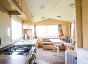 eine Küche und ein Wohnzimmer mit einem Herd und einem Sofa in der Unterkunft Willerby Magnum in Clacton-on-Sea