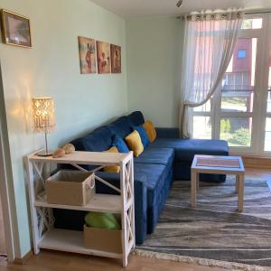 a living room with a blue couch and a table at Apartamentai Taikos 24 in Nida