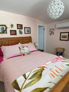 een slaapkamer met een bed met roze lakens en een kroonluchter bij Seabank House Bed and Breakfast Aloha in Pictou