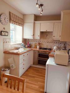 a kitchen with white cabinets and a white refrigerator at Boutique Cottage In The Heart Of Buxton Town in Buxton