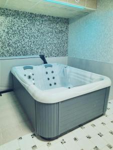 y baño con bañera y suelo de baldosa. en Horský Hotel Podjavorník, en Papradno