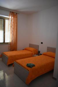 2 camas en una habitación con sábanas de color naranja en A casa di Gió e Chri, en Minturno