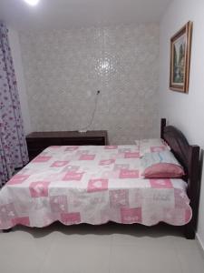 ein Schlafzimmer mit einem Bett mit einer rosa Decke in der Unterkunft GUARUJÁ ENSEADA CASA 6 PES PROX PRAIA in Guarujá