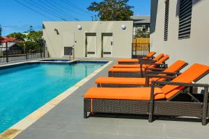 a pool with orange lounge chairs next to a swimming pool at Gladstone Central Plaza Official in Gladstone