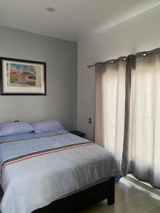 - une chambre avec un lit et une fenêtre avec des rideaux dans l'établissement Sol y Luna Teotihuacan, à San Sebastian Xolalpa