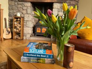 una mesa con libros y un jarrón con flores. en The Auld Kirk, en Kirkbean