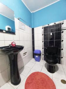 a bathroom with a black toilet and a sink at Samay Wasi - Aeropuerto in Lima