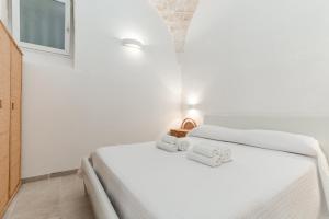 a white bedroom with a bed with towels on it at La Casetta di Chloè in Ostuni