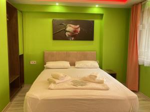 ein grünes Schlafzimmer mit einem Bett mit Handtüchern darauf in der Unterkunft verosuitotel in Konak