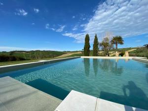a large swimming pool with blue water and trees at Casale Il Girasole in San Costanzo