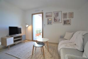 ein Wohnzimmer mit einem Sofa und einem TV in der Unterkunft STUDIO dernier étage avec terrasse - vue montagne in Cruseilles